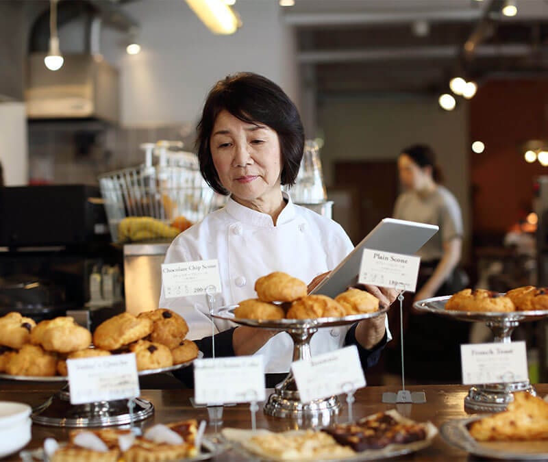 Der Inhaber einer kleinen örtlichen Bäckerei bei einer Bestandsaufnahme der ausliegenden Backwaren.