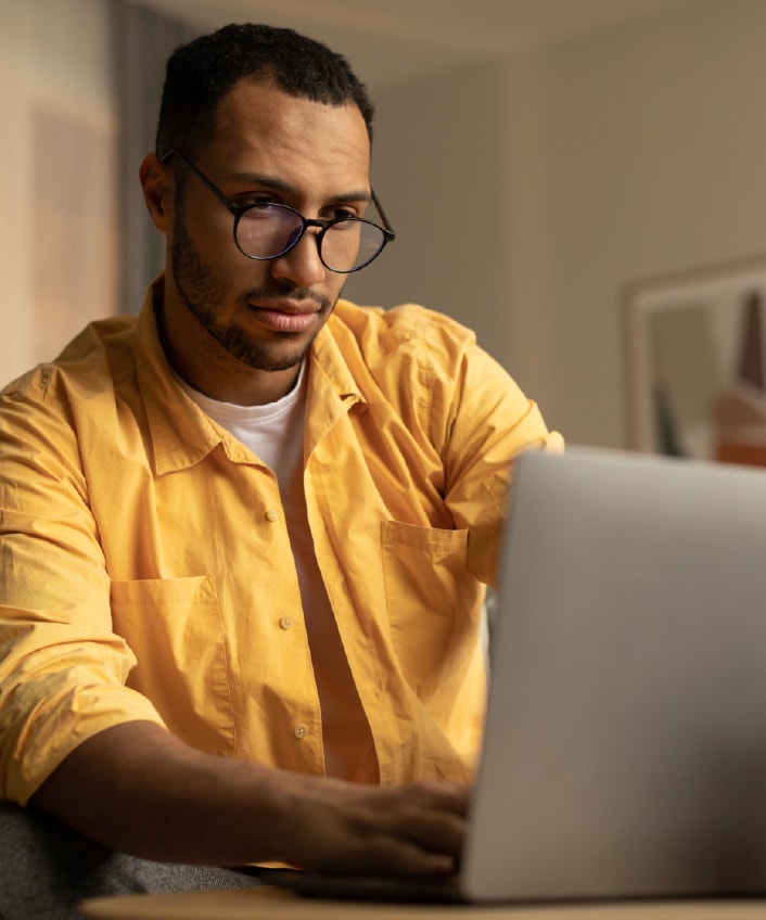 Ein Mann im gelben Hemd beim Betrachten eines möglicherweise mit Spyware infizierten Laptops.