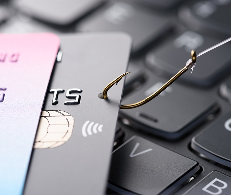 Kreditkarte auf einer Tastatur, die an einem Angelhaken hängt.