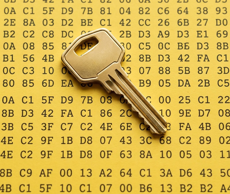 Ein goldener Schlüssel auf einem gelben Hintergrund, der mit Reihen von Hexadezimalcode gefüllt ist und Verschlüsselung sowie digitale Sicherheit symbolisiert