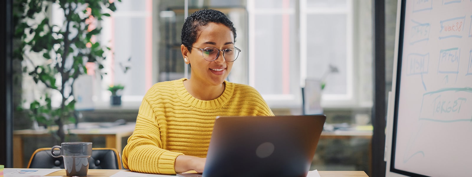 A woman in a yellow sweater looking up the answer to what is antivirus on a laptop.