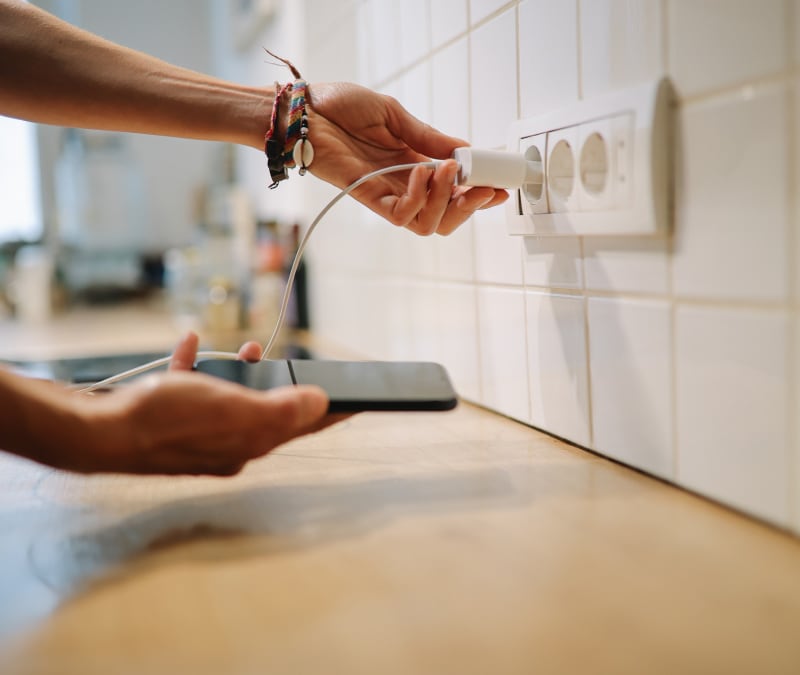 Eine Person, die ihr Smartphone zum Aufladen einsteckt, weil sich der Akku so schnell entlädt.