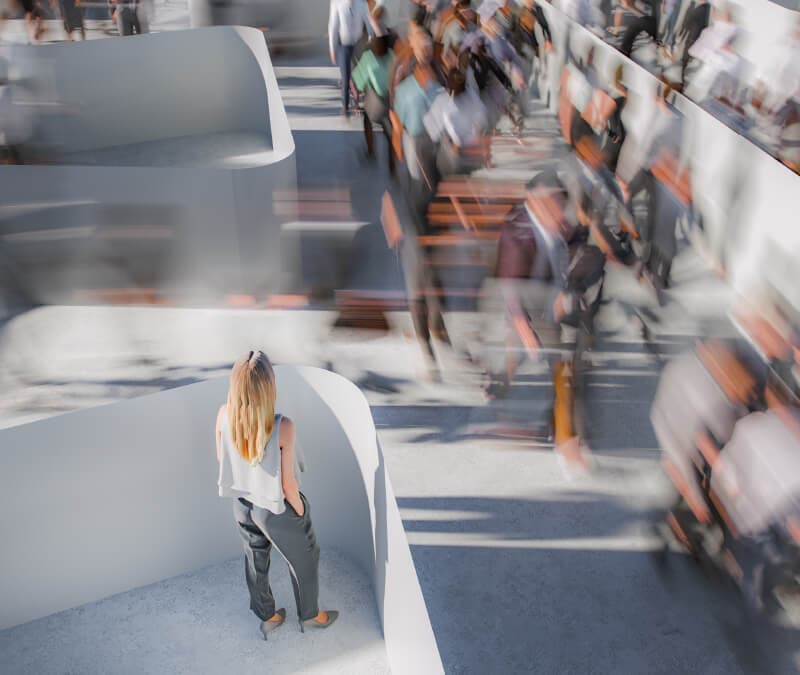 Eine Frau steht auf einer Plattform und beobachtet, wie Menschen vorbeirasen.