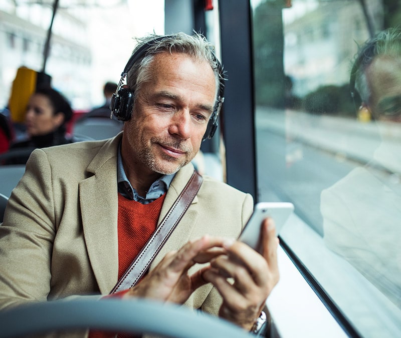 Ein Mann im Bus, der auf sein Handy blickt und sich dabei fragt, warum es so langsam ist.