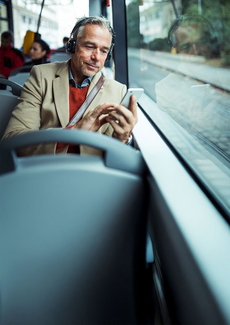 Ein Mann im Bus, der auf sein Handy blickt und sich dabei fragt, warum es so langsam ist.