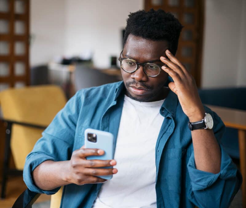 Ein Mann, der sich beim Betrachten seines Handys fragt, ob iPhones gehackt werden können 