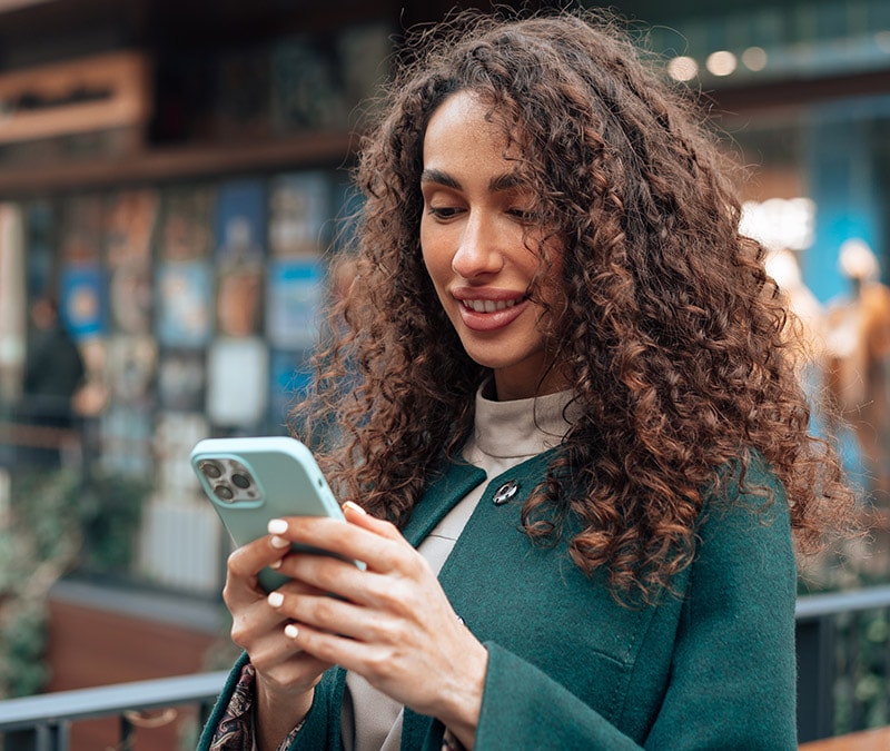  Eine Frau mit lockigem Haar überprüft ihr iPhone auf Viren. 