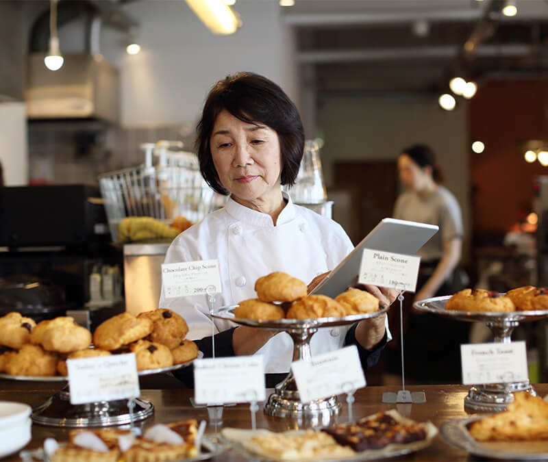 The owner of a small local bakery inventories baked goods on display.