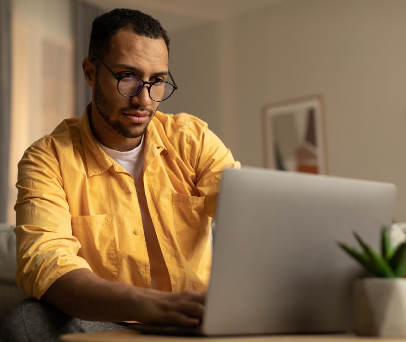 Ein Mann im gelben Hemd beim Betrachten eines möglicherweise mit Spyware infizierten Laptops.