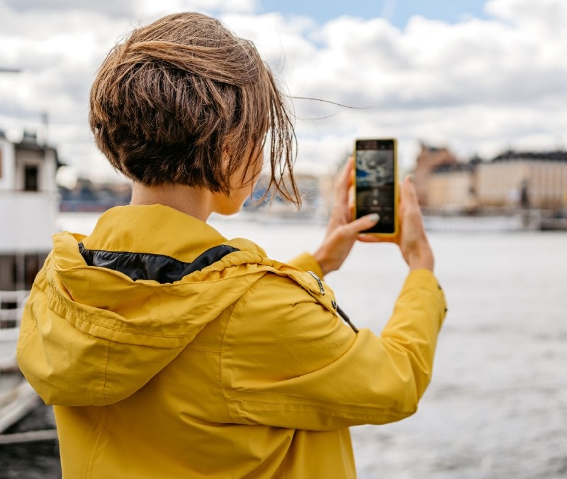 Eine Frau macht ein Foto, ohne zu wissen, dass ihre Handy-Kamera gehackt wurde.