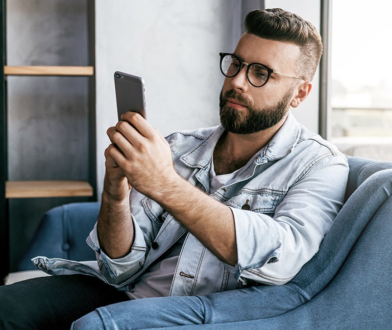 A man from Gen Z or a millennial casually using his smartphone, epitomizing millennials' digital behavior.