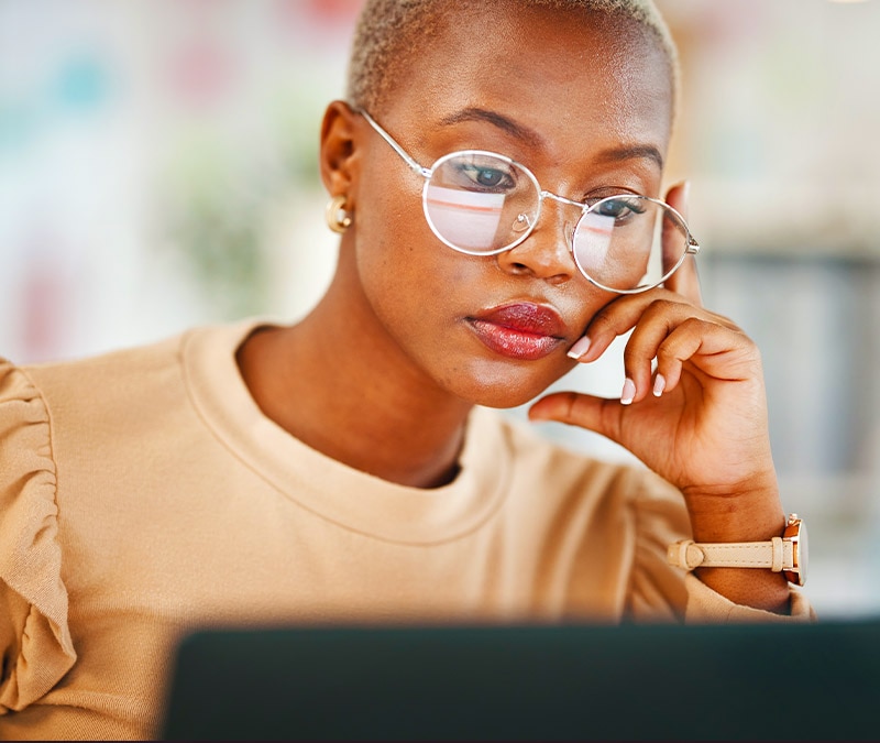 A woman is looking at her laptop, thinking what to do with a scammer who has her email. 