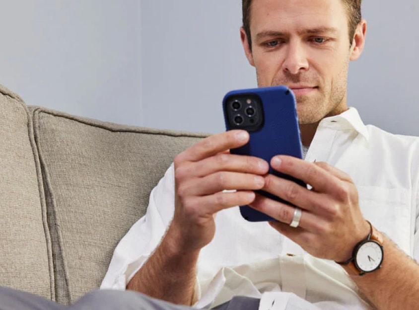 Mann auf Couch schaut auf Telefon