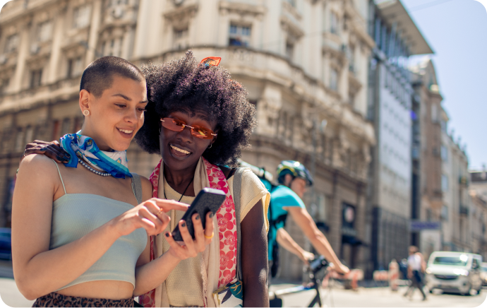 Zwei lächelnde Frauen, die auf ein Smartphone schauen